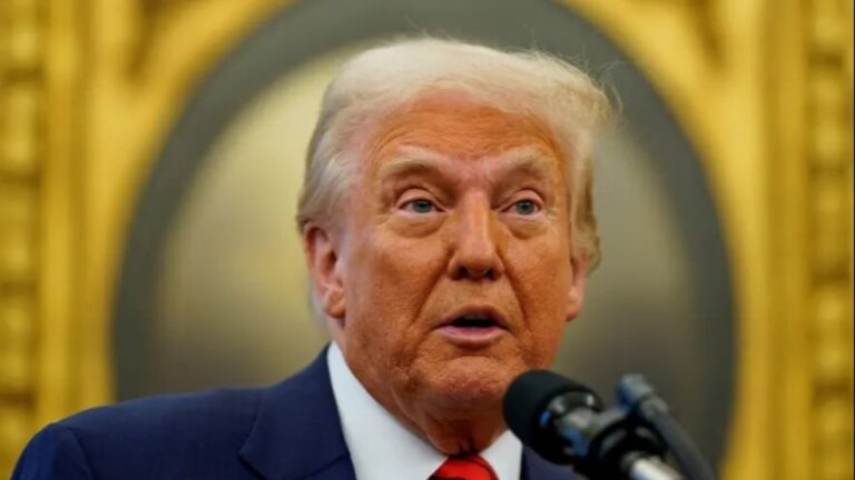 دونالد ترامپ در حال سخنرانی با پرچم آمریکا و نقشه ونزوئلا و گرینلند در پس‌زمینه